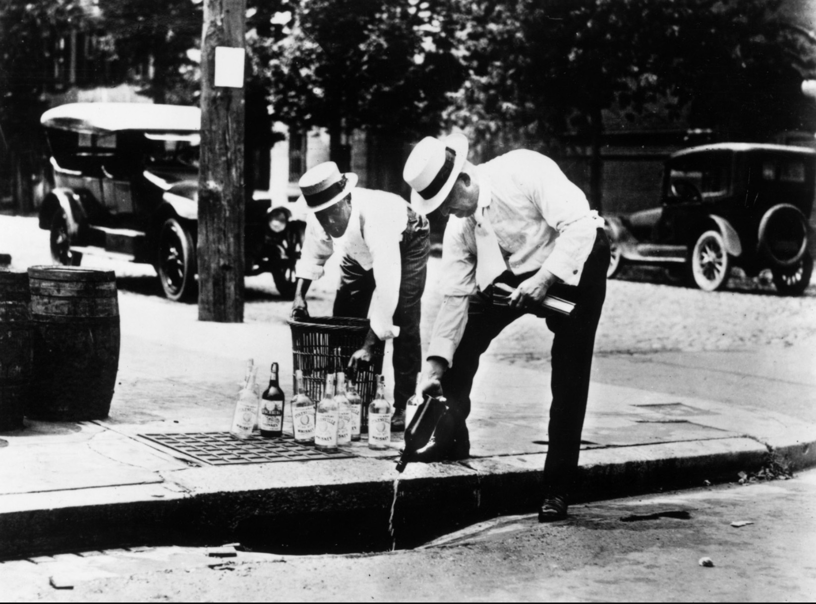 Two men pouring alcohol down the drain during prohibition 